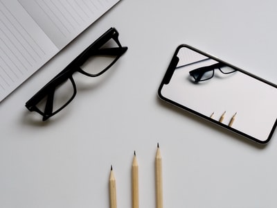 眼镜；银色iphonex；三支铅笔；笔记本平放摄影